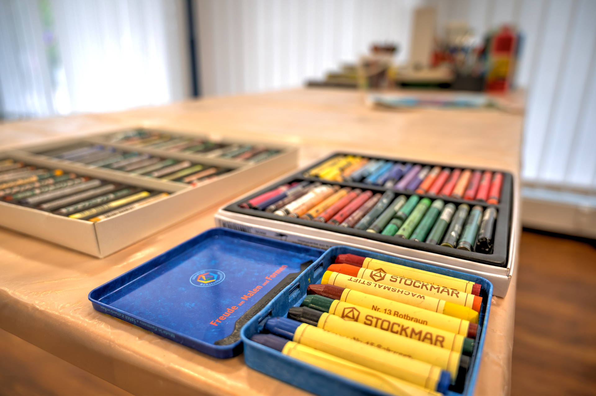 Verschiedene Dosen mit Wachsmalstiften auf einen Tisch in der Praxis